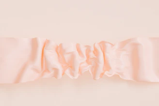 Soft blush pink fabric swatches layered elegantly on a warm beige background.