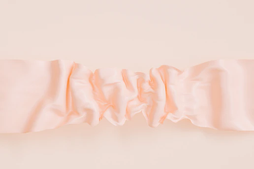 Soft blush pink fabric swatches layered elegantly on a warm beige background.