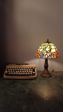A cozy workspace with a vintage typewriter and a green emerald tunic draped over a chair.