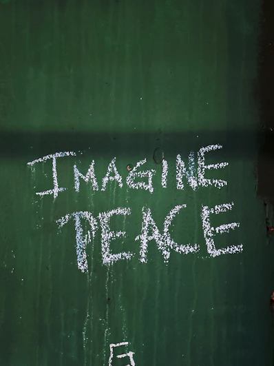 a chalk drawing on a green wall that says imagine peace