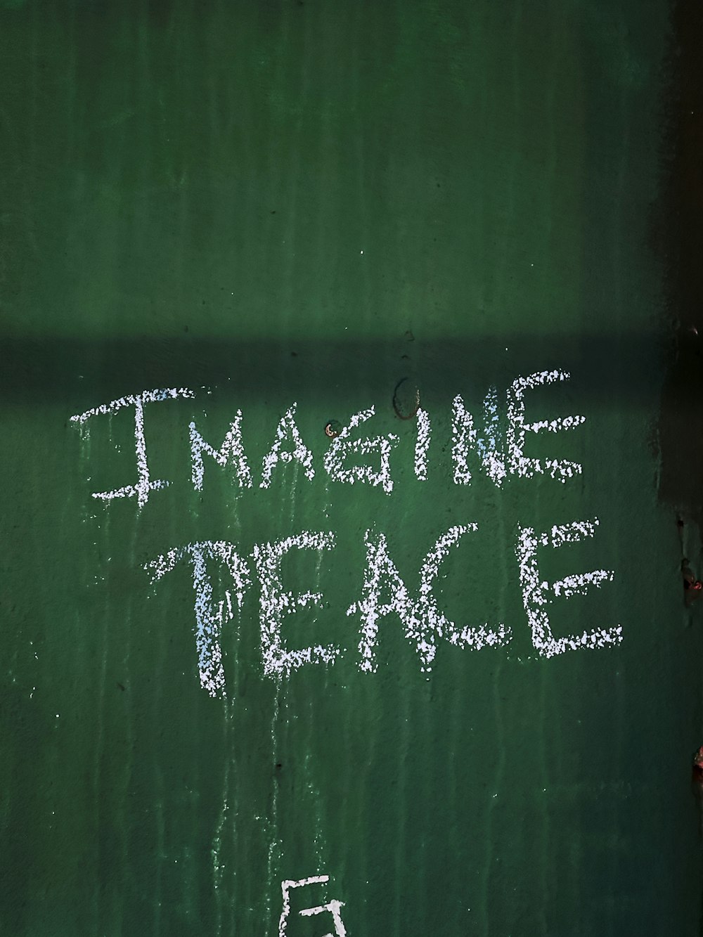 Eine Kreidezeichnung auf einer grünen Wand mit der Aufschrift "Stell dir den Frieden vor"