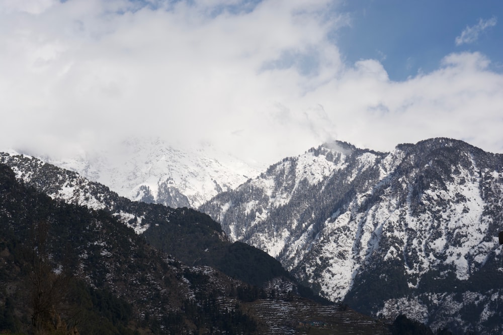 a mountain range covered in snow under a cloudy sky