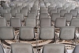 A large array of gray chairs is neatly arranged in rows, set on a patterned mosaic tile floor.