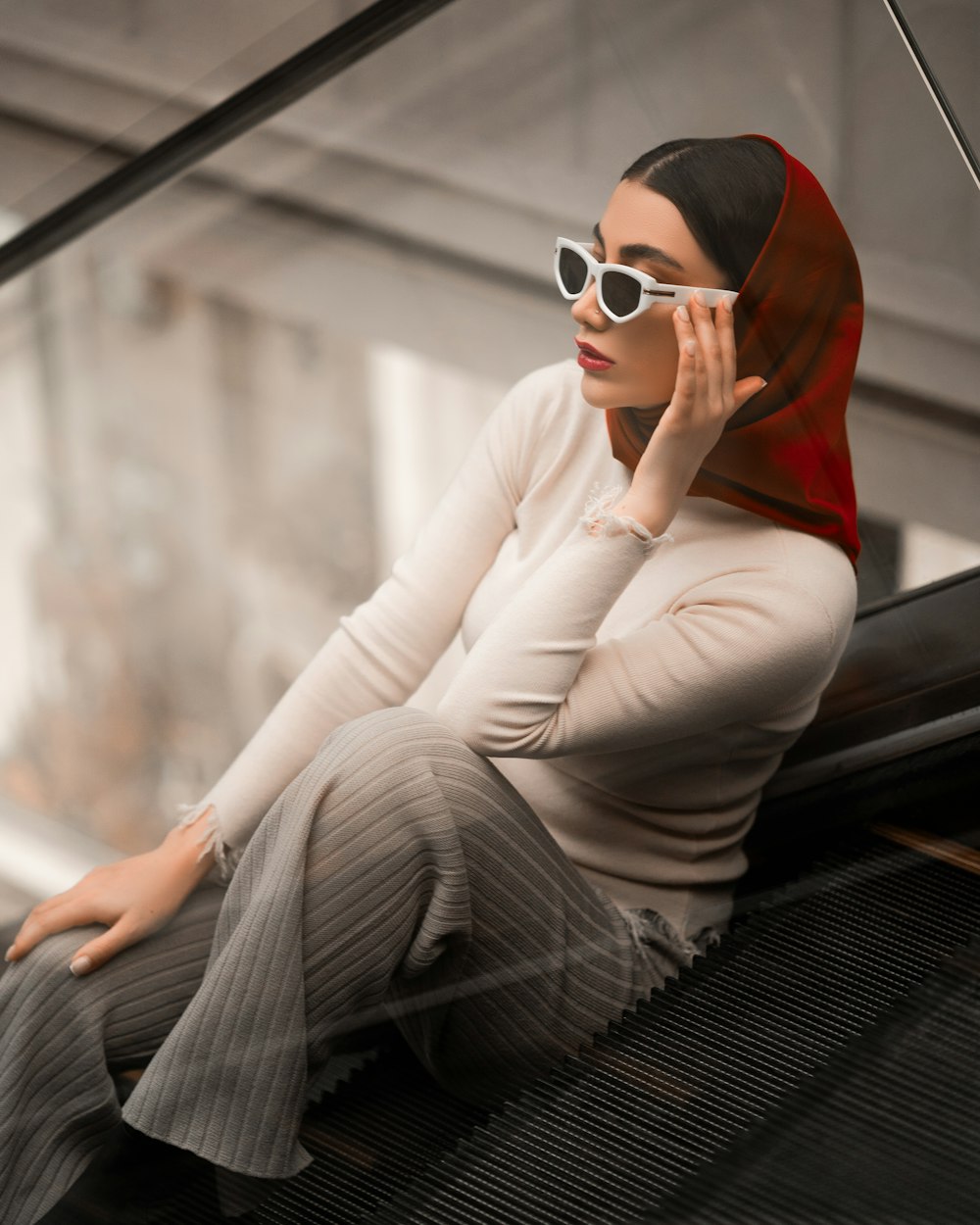 a woman sitting on top of an escalator talking on a cell phone