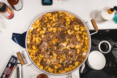 Ingredients laid out on a kitchen counter: shredded chicken, crispy bacon, elbow macaroni, ranch seasoning, and shredded cheese.