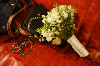 An elegant navy blue clutch placed beside a bouquet of fresh flowers on a café table.