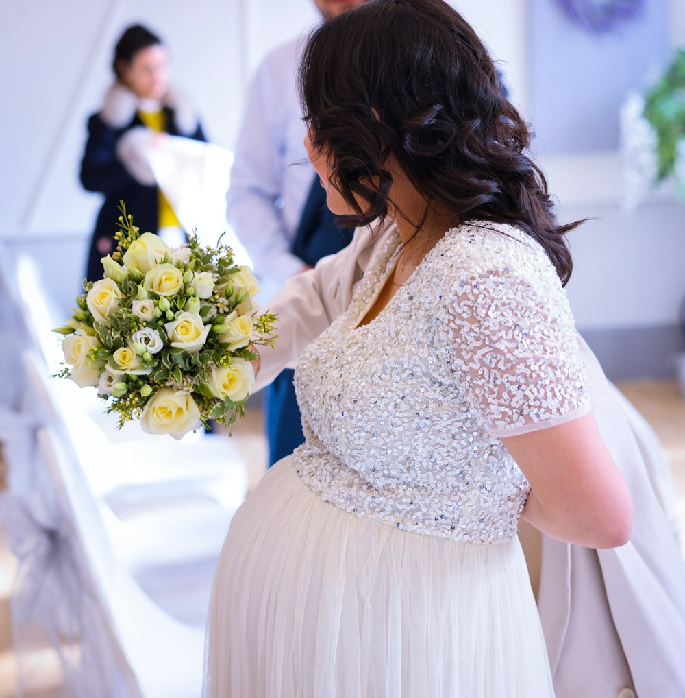 a woman in a white dress holding a bouquet of flowers