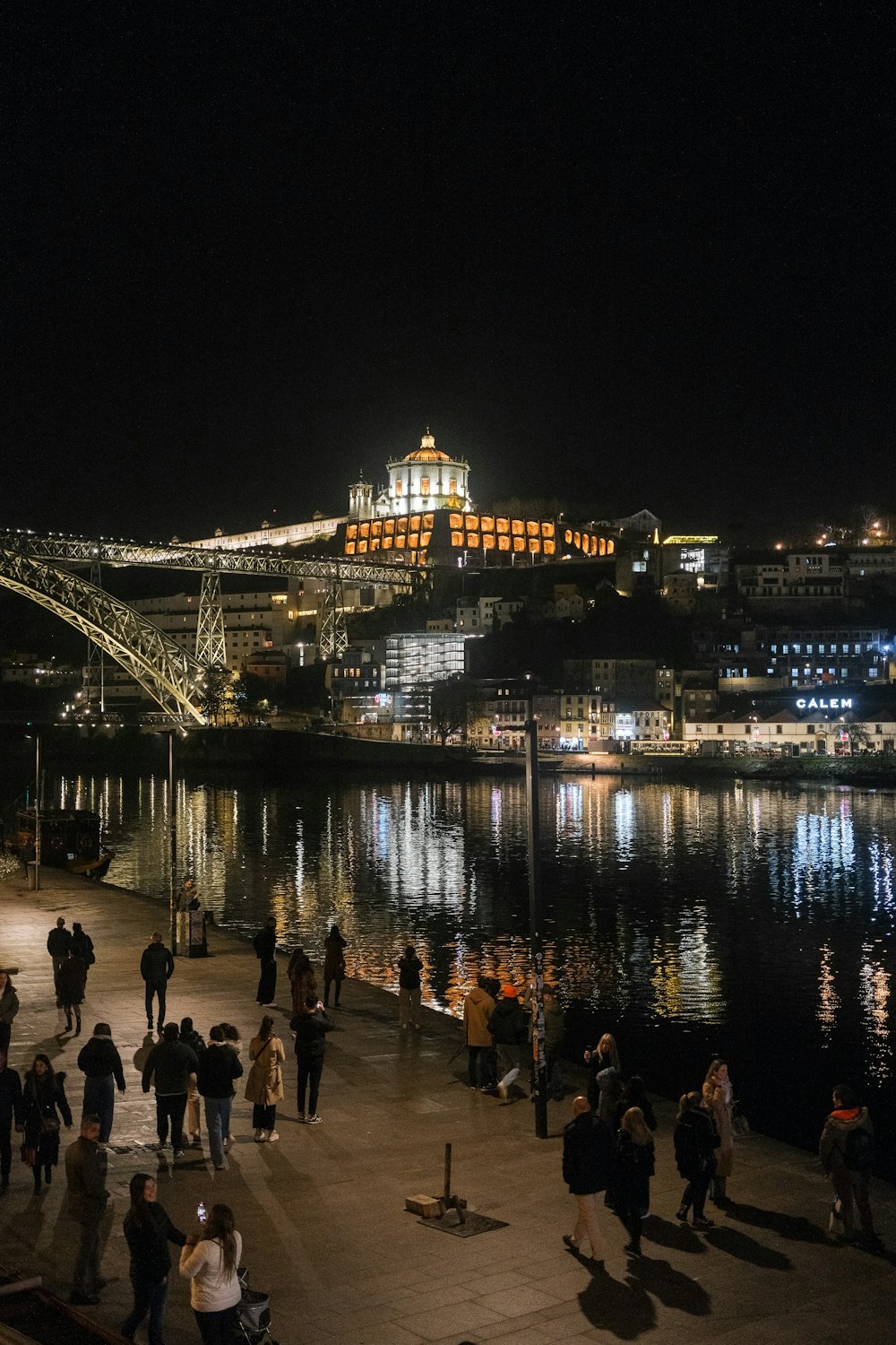 a group of people walking along a river at night