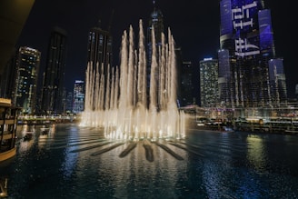 Night view of Dubai Fountain show with illuminated water jets.