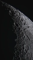 A close-up of the moon’s cratered surface illuminated by sunlight.