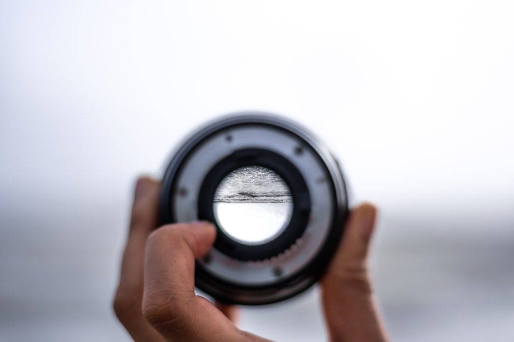 a person holding a camera lens in their hand