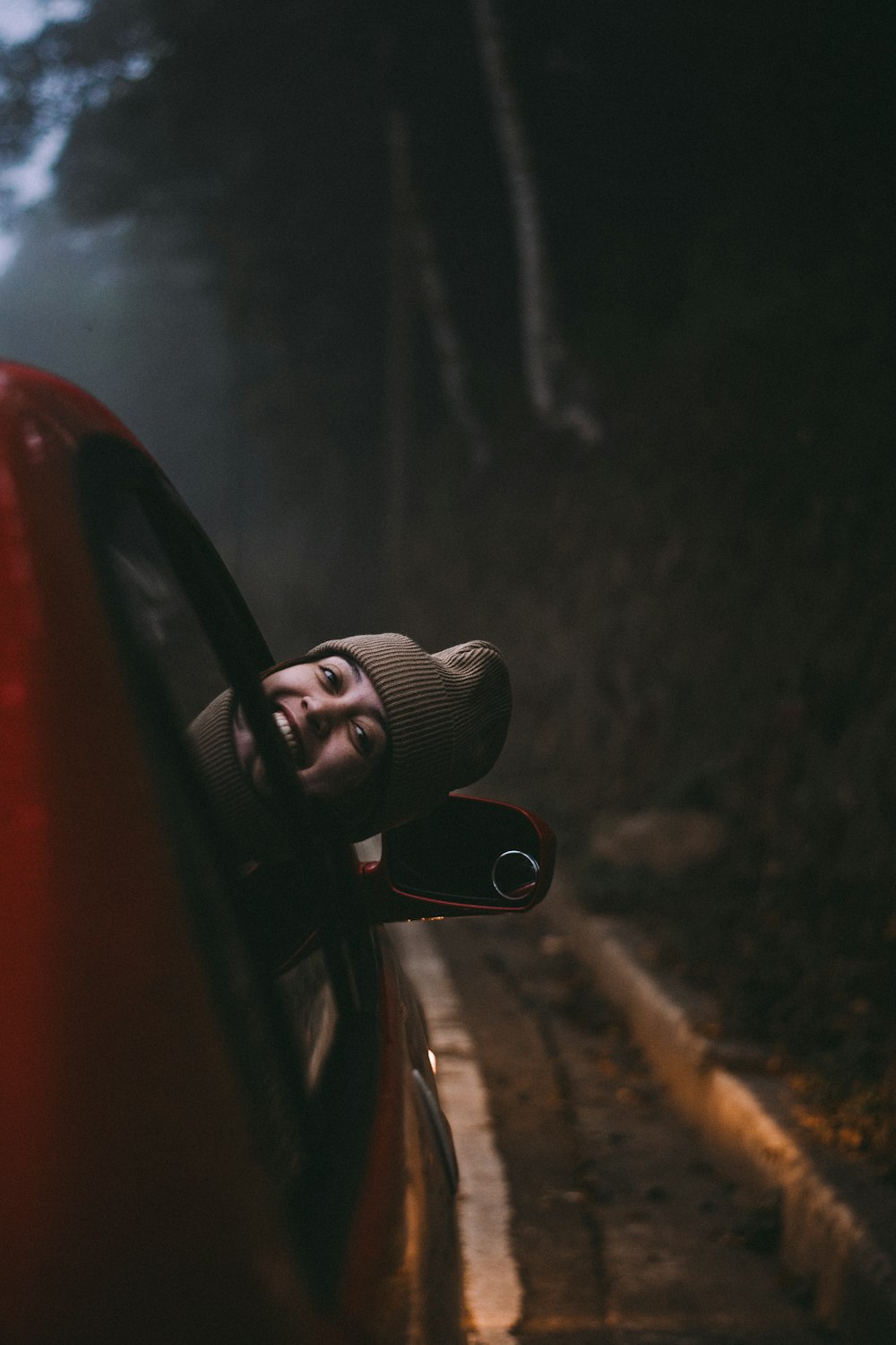 a man leaning out the window of a red car