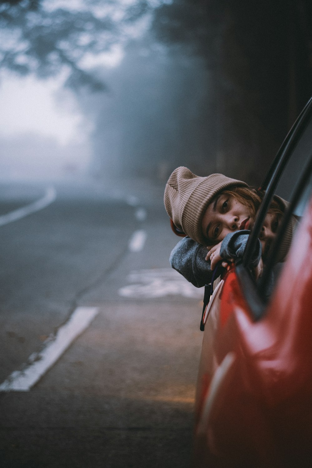 a woman leaning out the window of a red car