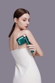 a woman in a white dress holding a green hair dryer