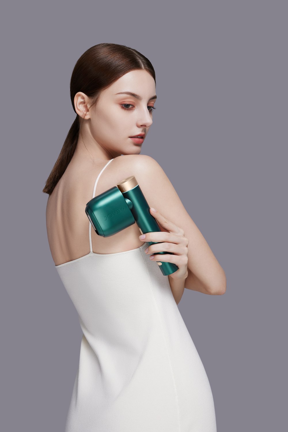 a woman in a white dress holding a green hair dryer