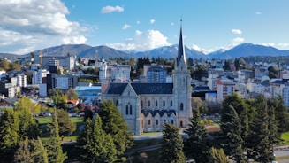 a church in the middle of a city with mountains in the background