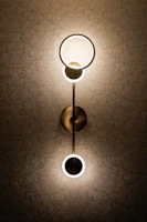 A contemporary wall sconce highlighting textured wallpaper in a serene bedroom.