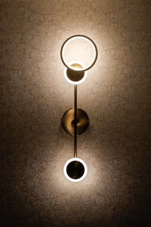 A contemporary wall sconce highlighting textured wallpaper in a serene bedroom.