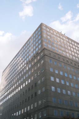 A modern office building with large windows reflecting the sky.