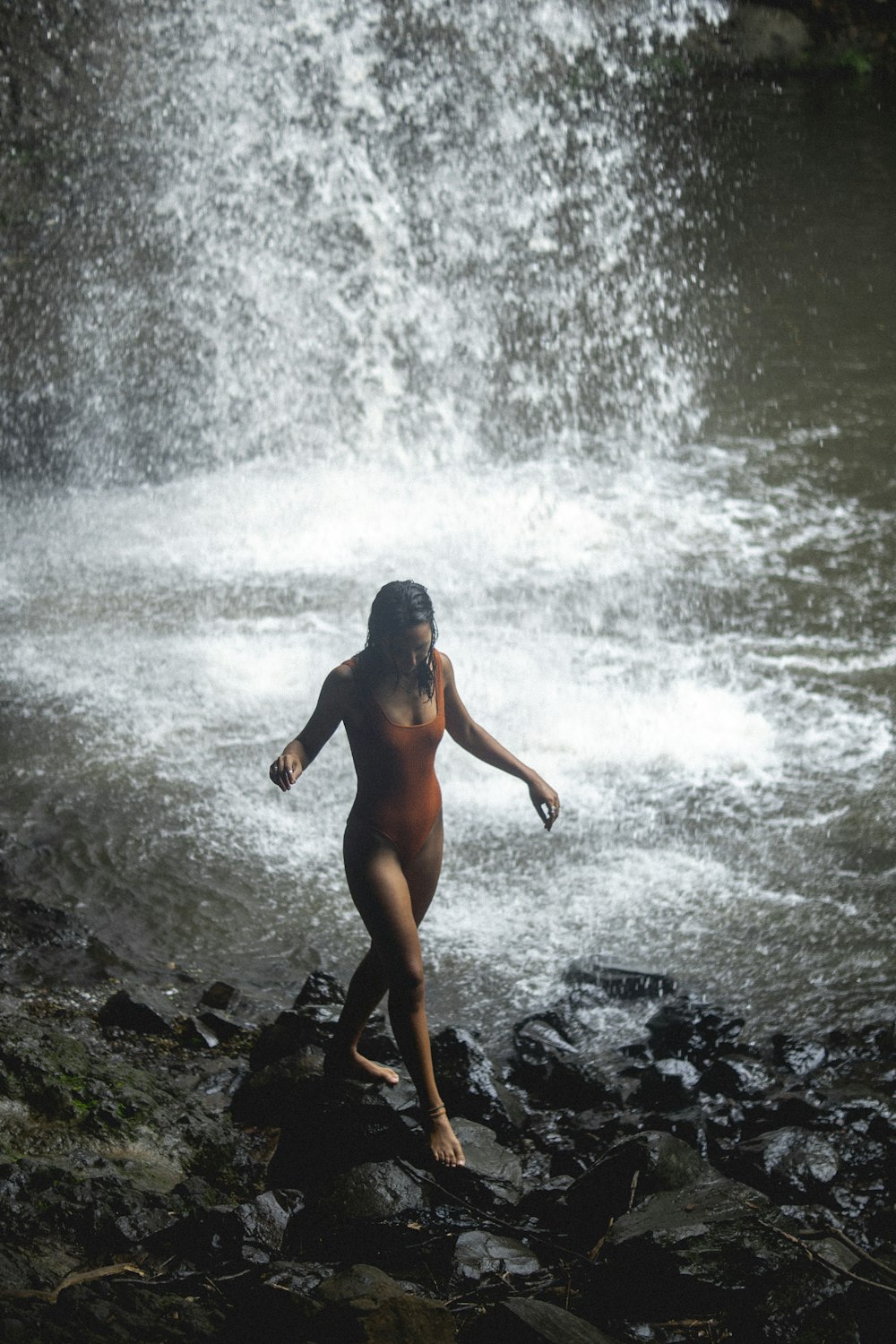 eine nackte Frau steht vor einem Wasserfall