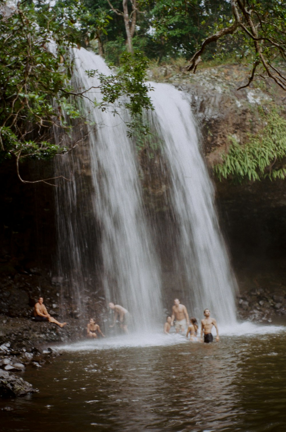 a group of people standing under a waterfall