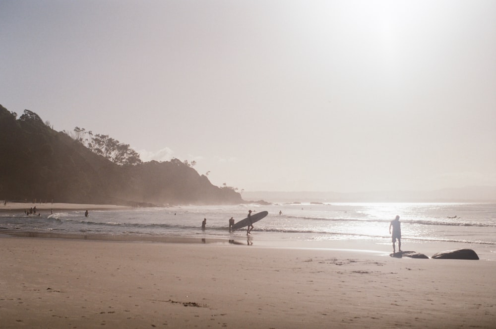 a group of people standing on top of a sandy beach