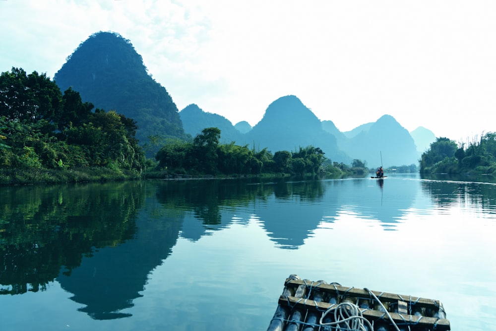 a boat floating on top of a lake surrounded by mountains