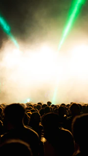 Wide angle shot of an underground techno event with a crowd immersed in dark, atmospheric lighting.