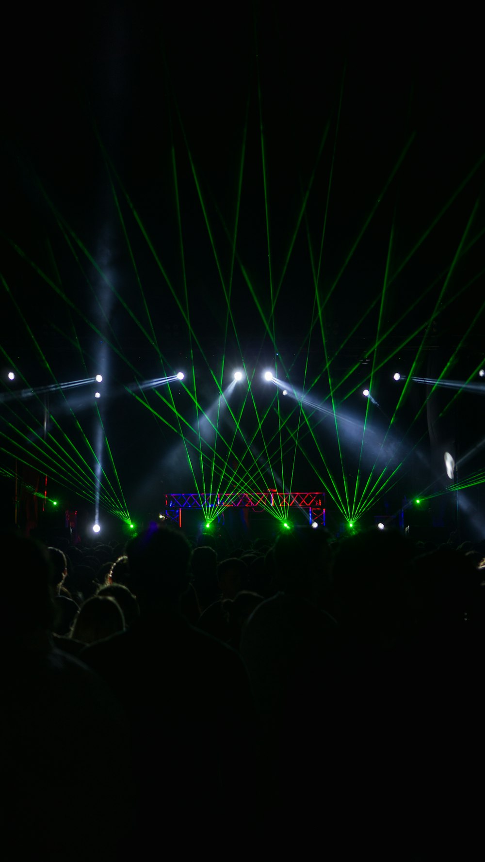 a crowd of people standing around a stage with green and white lights