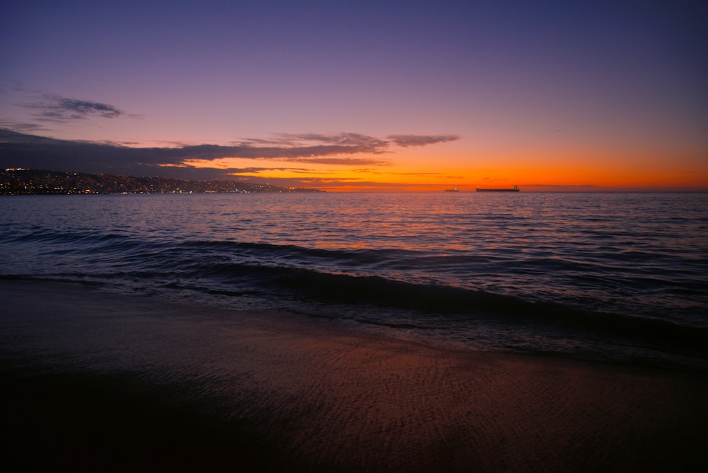 a sunset over the ocean with a boat in the distance