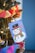 A decorated Christmas tree with a handmade snowman card hanging on it. The snowman is wearing a black hat and a colorful scarf. Surrounding the card are various colored paper chains and festive lights, creating a cheerful holiday atmosphere.
