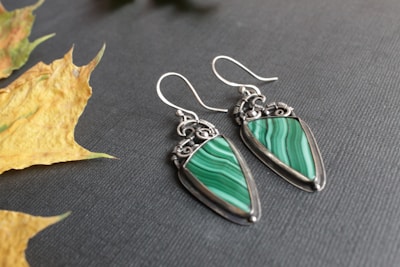 Close-up of lavender and pastel lime green polymer clay earrings arranged on a soft fabric background.