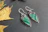 Elegant earrings with eco-friendly gemstones sparkling under natural light on a wooden display.