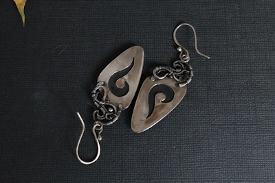Pair of handcrafted earrings featuring subtle metallic details and smooth curves.