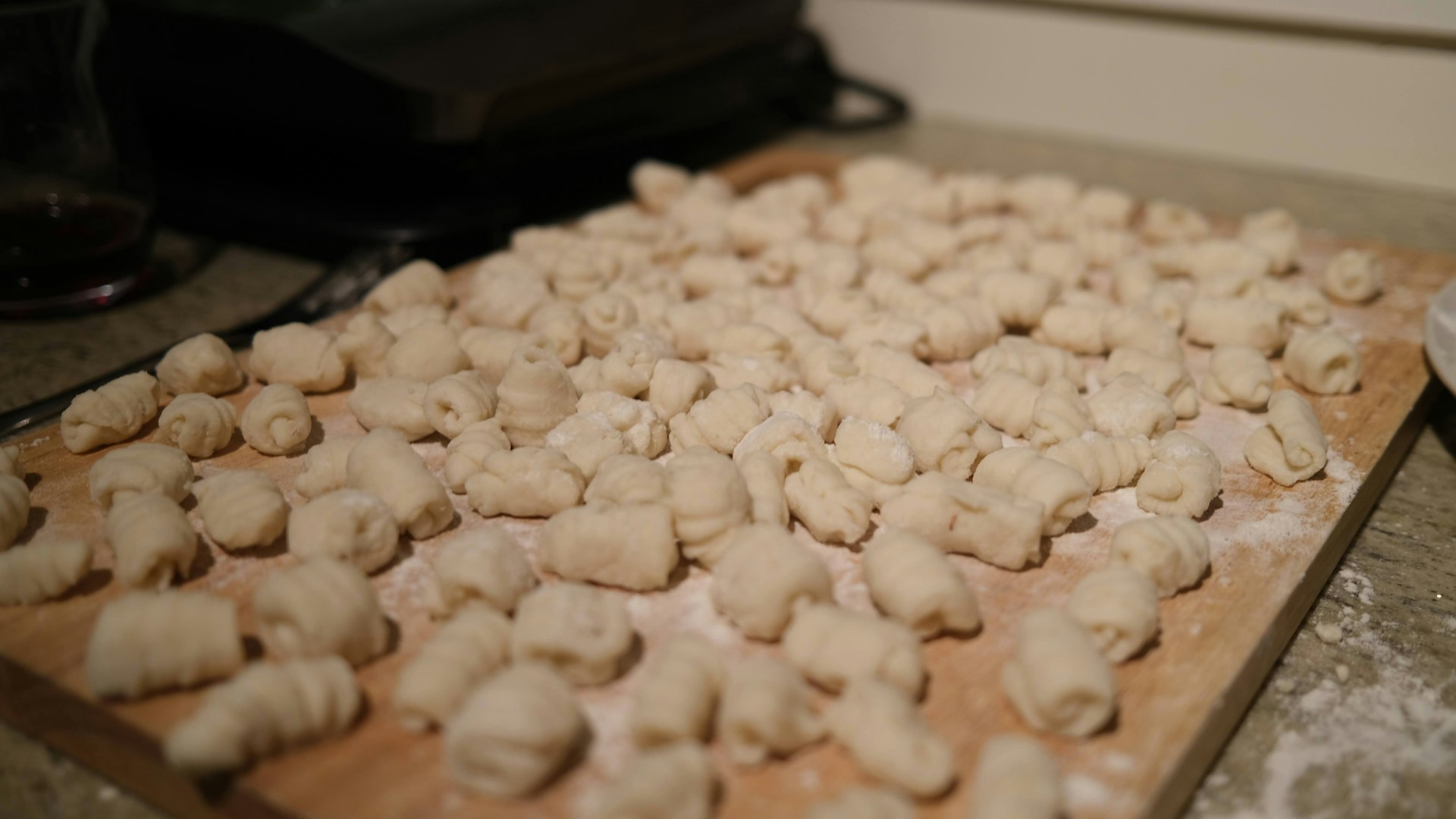 a wooden cutting board topped with dumplings on top of a counter