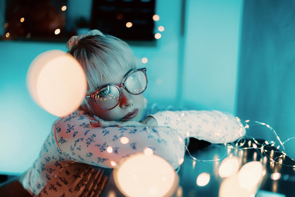 a woman wearing glasses sitting in front of a table