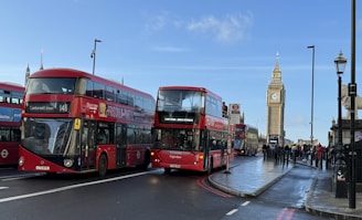 A charming street scene in London featuring a red double-decker bus passing by Big Ben on a sunny day.