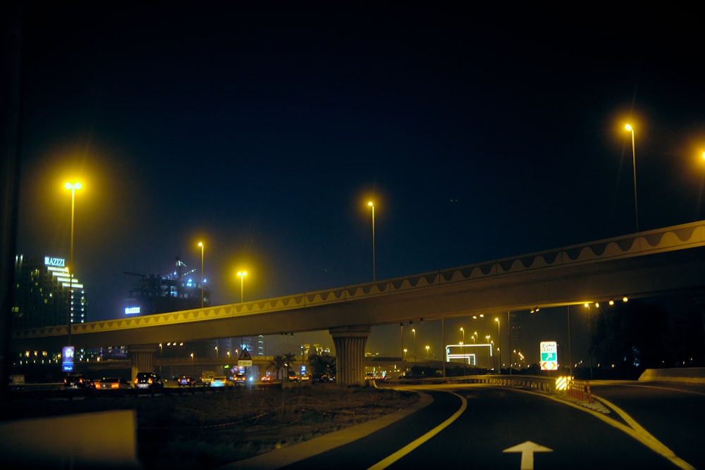 a highway at night with street lights and buildings in the background