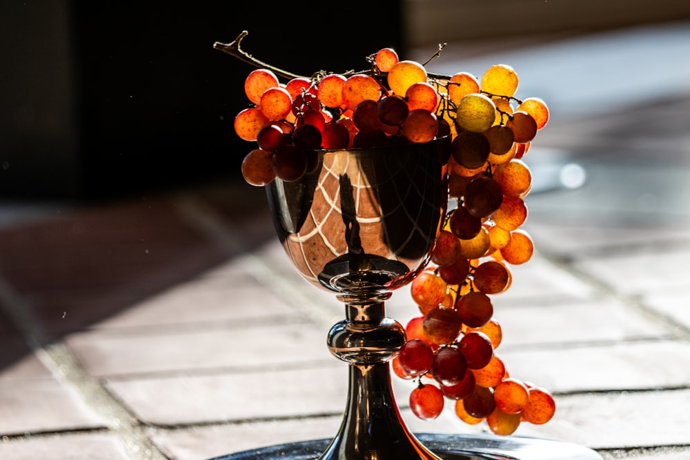 a goblet filled with grapes on top of a table