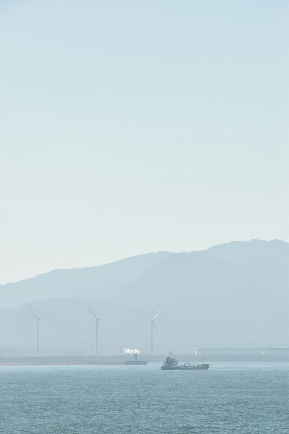 a boat in the water with wind mills in the background