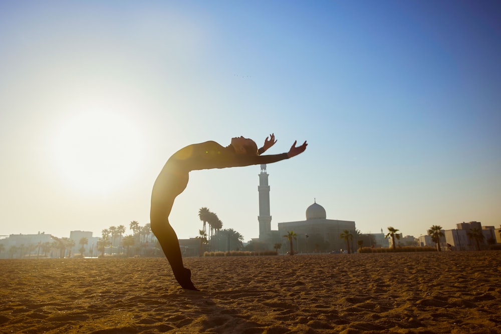 a woman standing on one leg in the sand