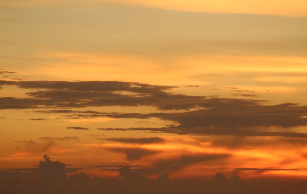 a plane flying in the sky at sunset