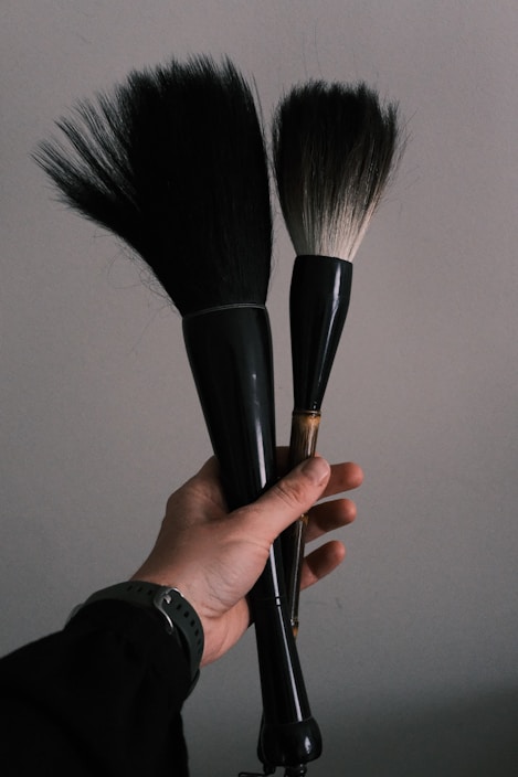 A stylist's hands holding premium brushes and combs ready for use.