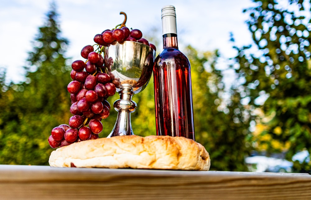 a bottle of wine, bread and a chalice on a table