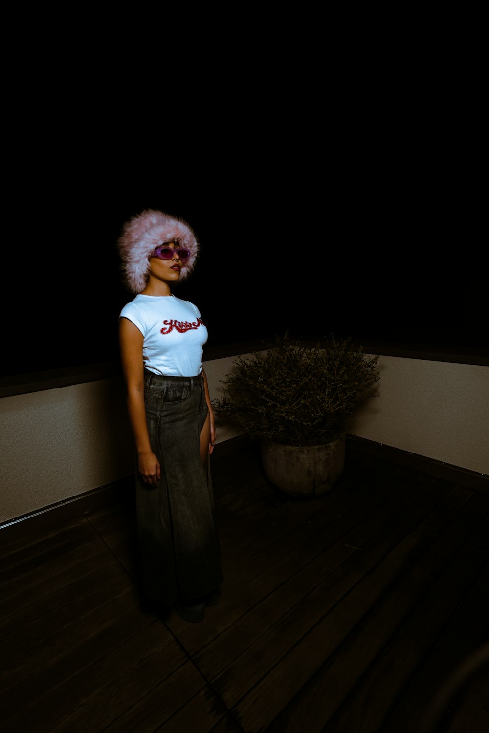 a woman with a pink afro standing on a wooden floor