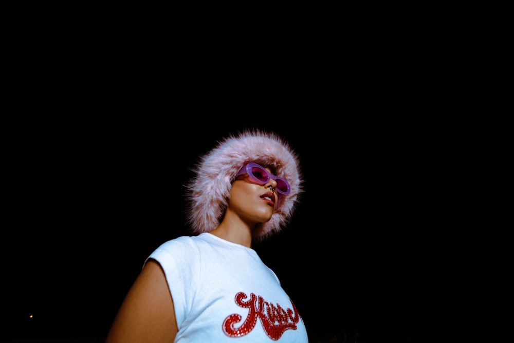 a woman wearing a white shirt and a pink fur hat
