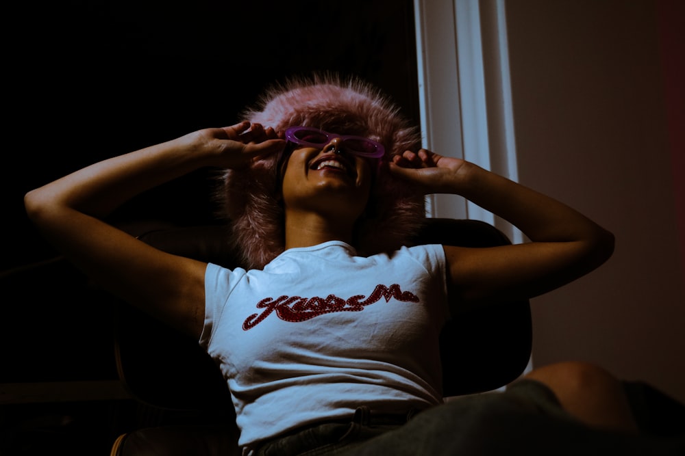 a woman wearing a white shirt and a pink furry hat