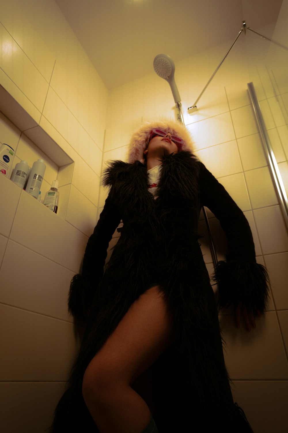 a woman in a furry coat standing in a bathroom