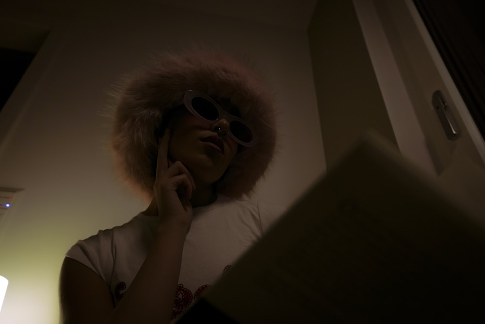 a woman wearing a fur hat and sunglasses talking on a cell phone