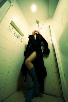 a woman standing in a bathroom with a coat on